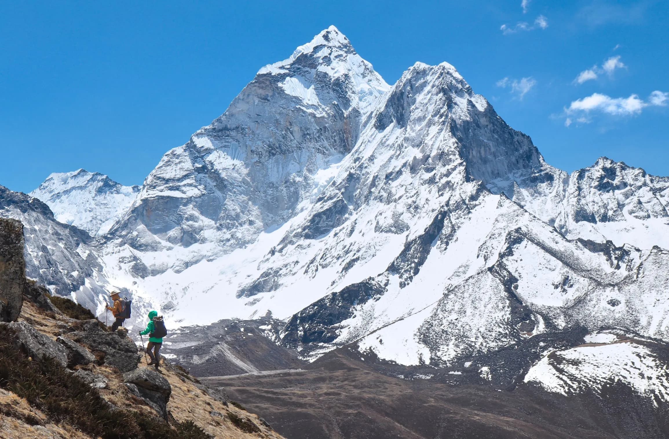 Excursionistas en la ruta al Campamento Base del Everest con los picos nevados del Himalaya al fondo.